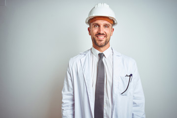 Young handsome engineer man wearing safety helmet over isolated background with a happy and cool smile on face. Lucky person.