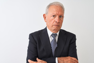 Senior grey-haired businessman wearing suit standing over isolated white background skeptic and nervous, disapproving expression on face with crossed arms. Negative person.