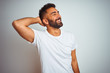 © Krakenimages.com - Young indian man wearing t-shirt standing over isolated white background smiling confident touching hair with hand up gesture, posing attractive and fashionable