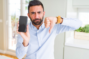 Sticker - Handsome hispanic business man showing smartphone screen with angry face, negative sign showing dislike with thumbs down, rejection concept