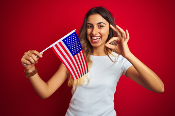 Sticker - Young woman holding united states of america flag over red isolated background doing ok sign with fingers, excellent symbol