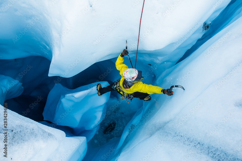Ice climber on piller inside vertical ice cave on the Matanuska Glacier. - obrazy, fototapety, plakaty 
