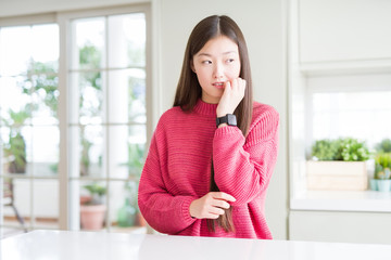 Sticker - Beautiful Asian woman wearing pink sweater on white table looking stressed and nervous with hands on mouth biting nails. Anxiety problem.