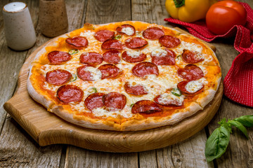 Wall Mural - Pepperoni pizza on board on old wooden table