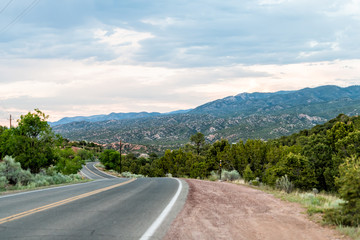 Sunset on Bishops Lodge Road in Santa Fe, New Mexico with pink sunlight on green plants and road to Tesuque residential community