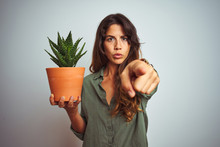 Young Beautiful Woman Holding Cactus Pot Over White Isolated Background Pointing With Finger To The Camera And To You, Hand Sign, Positive And Confident Gesture From The Front