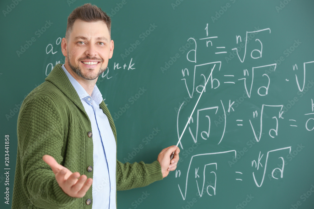 Handsome math teacher near blackboard in classroom