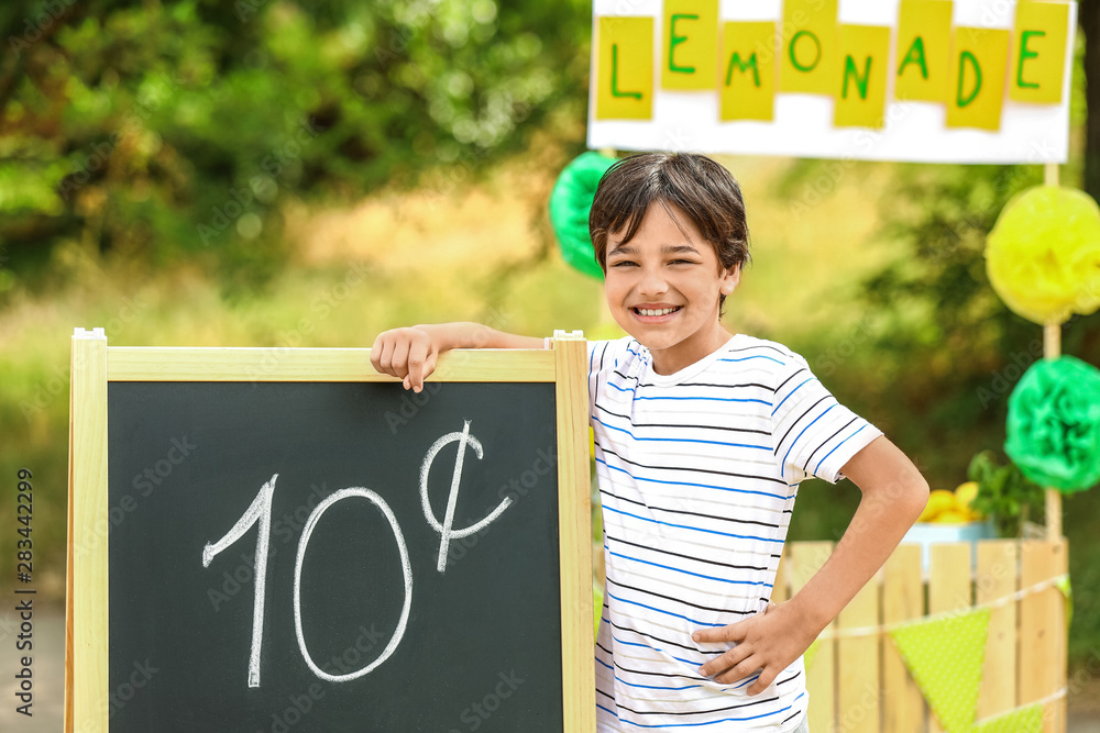 Cute little boy selling lemonade in park