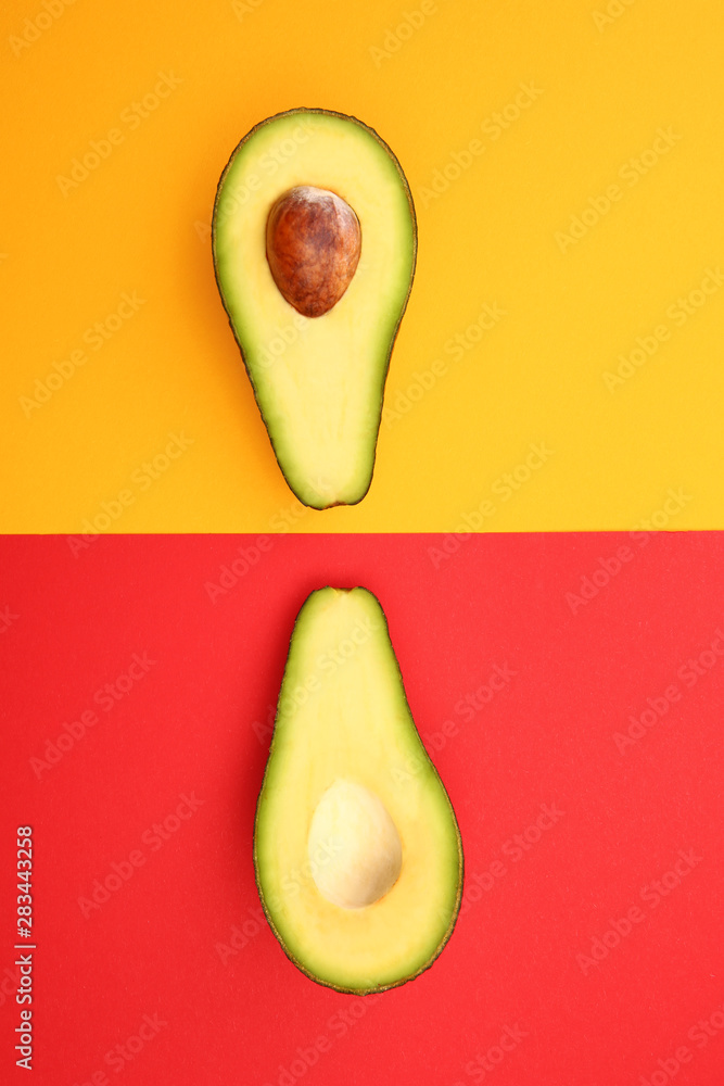 Halves of ripe avocado on color background