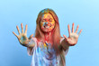 © alfa27 - positive smiling girl with closed eyes showing her dirty palms, looking forward holi festival. isolated blue background, studio shot