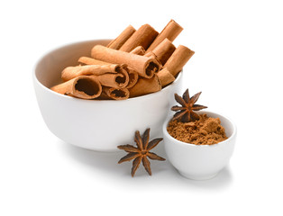 Bowls with aromatic cinnamon sticks and powder on white background