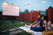 Couple in love watching a movie, in twilight, outside on the lawn in a courtyard