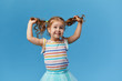© oes - Portrait of surprised smiling cute little toddler girl. child standing isolated over blue background. Looking at camera and laughs