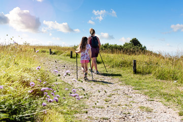 Wall Mural - beautiful girl and her mom doing nordic walking with sticks in the countryside