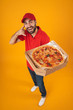 © Drobot Dean - Full length image of positive delivery man in red uniform smiling and holding pizza box