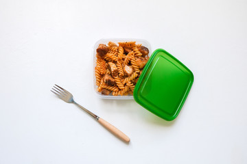 Fusilli pasta with meat bolognese tomato sauce. Business lunch in a plastic box container.