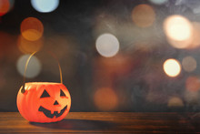 Halloween Concept - Orange Plastic Pumpkin Lantern On A Dark Wooden Table With Blurry Sparkling Light In The Background, Trick Or Treat, Close Up.