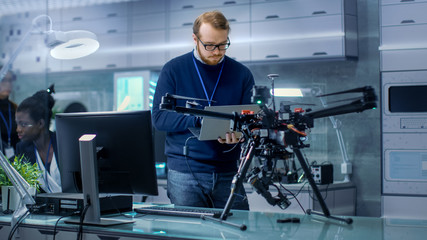 Wall Mural - young male engineer programs drone while holding laptop in his hands. he works in a bright modern hi