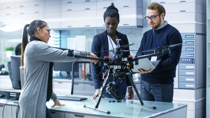 Wall Mural - multi ethnic team of young female and male engineers working on modern drone prototype. they're in a