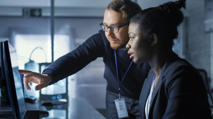 Wall Mural - african american female scientist works on a computer and having discussion with caucasian male coll