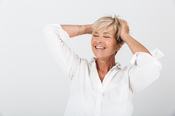 Portrait of joyous adult woman with short blond hair grabbing her head and laughing at camera