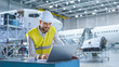 © Gorodenkoff - Engineer in Safety vest Working on Computer in Aircraft Maintenance Hangar
