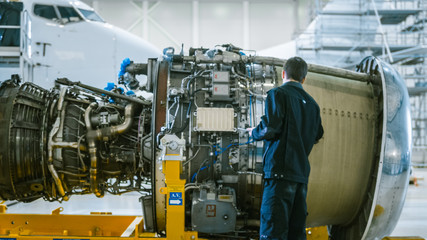 Aircraft Maintenance Mechanic Inspecting and using Tablet Airplane Jet Engine in Hangar