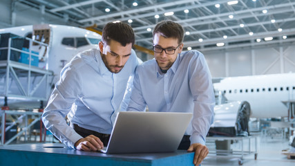 Two Aircraft Mechanics Working and Having Conversation next to Laptop Computer