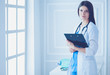 © lenets_tan - Beautiful doctor standing in a consulting room with a folder in her hands, thinking