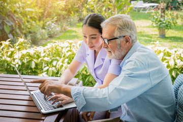 Caregiver assist senoir eldery man typing using notebook laptop computer connect to Internet