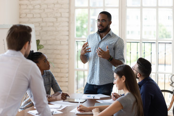 serious black manager talk to diverse staff people at meeting