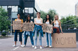© LIGHTFIELD STUDIOS - full length view of multiethnic feminists holding placards with slogans on street