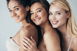 © LIGHTFIELD STUDIOS - three smiling multiethnic girls in underwear embracing isolated on grey