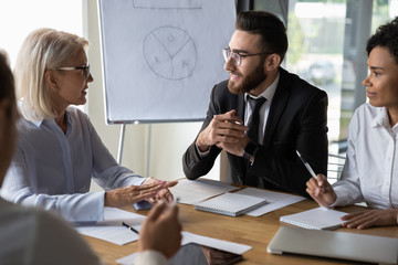 Canvas Print - Diverse business partners discussing project, mature leader holding briefing