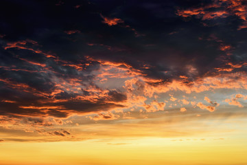 Wall Mural - red orange reflections of the setting sun on dark thunderclouds. scenic storm clouds lit by the last