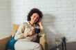 © Mediteraneo - African American woman in her living room drinking holding a coffee tea mug