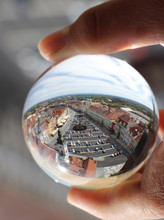 Market Square Of Hradec Kralove In Lens Ball Which Photographer Is Holding In Fingers. Crystal Ball Wih Recletion Of Hradec Kralove In Morning