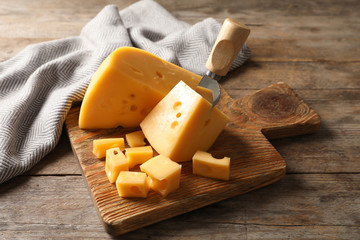 Serving board with delicious cheese on wooden table