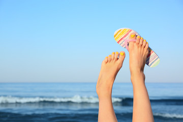 Wall Mural - Closeup of woman wearing flip flop near sea, space for text. Beach accessories
