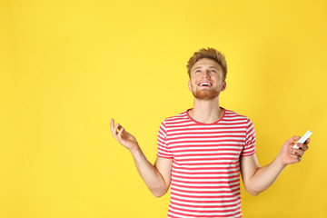 Wall Mural - Young man with air conditioner remote on yellow background. Space for text