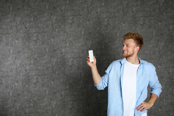 Poster - Young man with air conditioner remote on grey background. Space for text