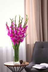 Canvas Print - Vase with beautiful pink gladiolus flowers on wooden table in room, space for text