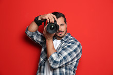 Young Professional Photographer Taking Picture On Red Background