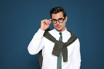 Wall Mural - Portrait of handsome young man wearing glasses on blue background