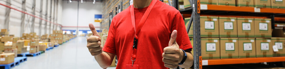 Wall Mural - Logistics warehouse keeper in red t-shirt against goods close-up.