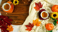 Autumn Fall Theme Flatlay Overhead With Cosy Sweater, Bagels, Cups Of Herbal Tea And Scattered Maple Leaves.