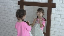 Girl Of Moda. Little Girl At The Mirror With A Beautiful White Dress.