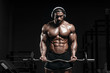© Fotokvadrat - Muscular athletic bodybuilder man hard training in gym over dark background with dramatic light with barbell in strong pumped hands