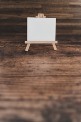 black canvas miniature surrounded by fairy lights on wooden desk with copyspace