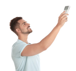 Wall Mural - Happy young man operating air conditioner with remote control on white background